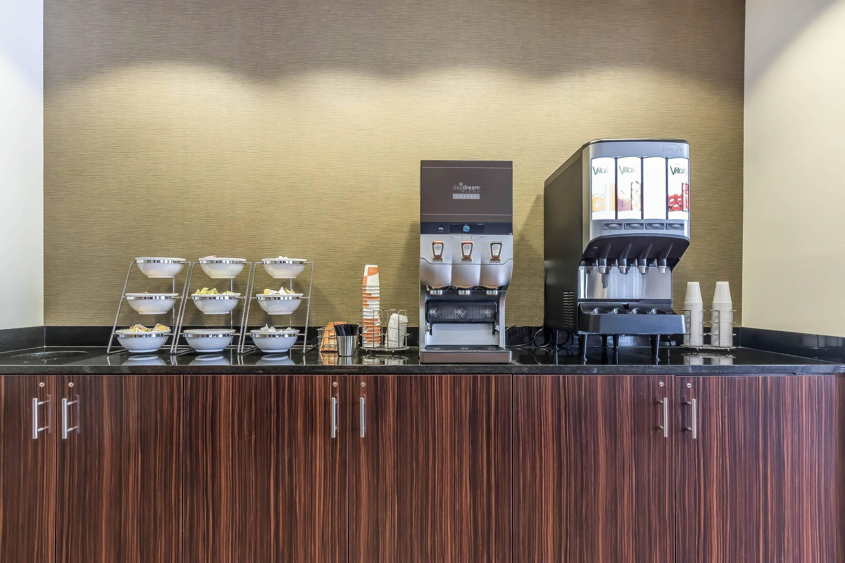 A coffee station with multiple beverage dispensers and bowls of snacks.