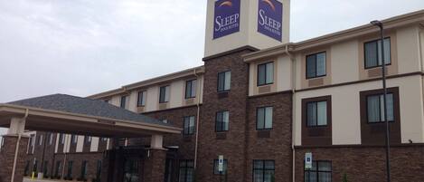 A Sleep Inn & Suites building with a covered entrance, multiple windows, and a parking area with handicapped accessibility signs.