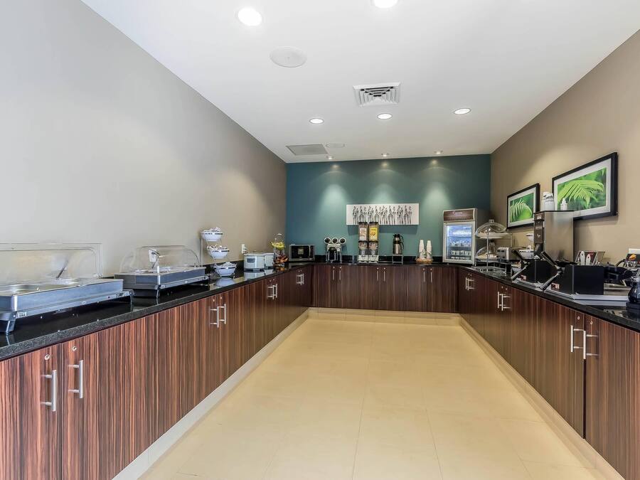 Cozinha moderna com armários de madeira, bancada preta e diversos eletrodomésticos.