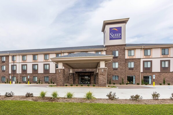 A Sleep Inn & Suites hotel with a modern brick facade, a covered entrance, and a parking lot.