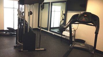 A gym with cardio machines, a treadmill, and a weight machine.
