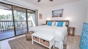 A bedroom with a large bed, a bench, a basket, a dresser, and a painting on the wall. - Portside Resort by Panhandle Getaways (Panama City Beach)