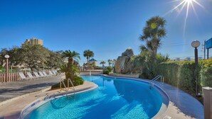 A swimming pool with a curved edge, surrounded by palm trees and a rock formation. - Portside Resort by Panhandle Getaways (Panama City Beach)