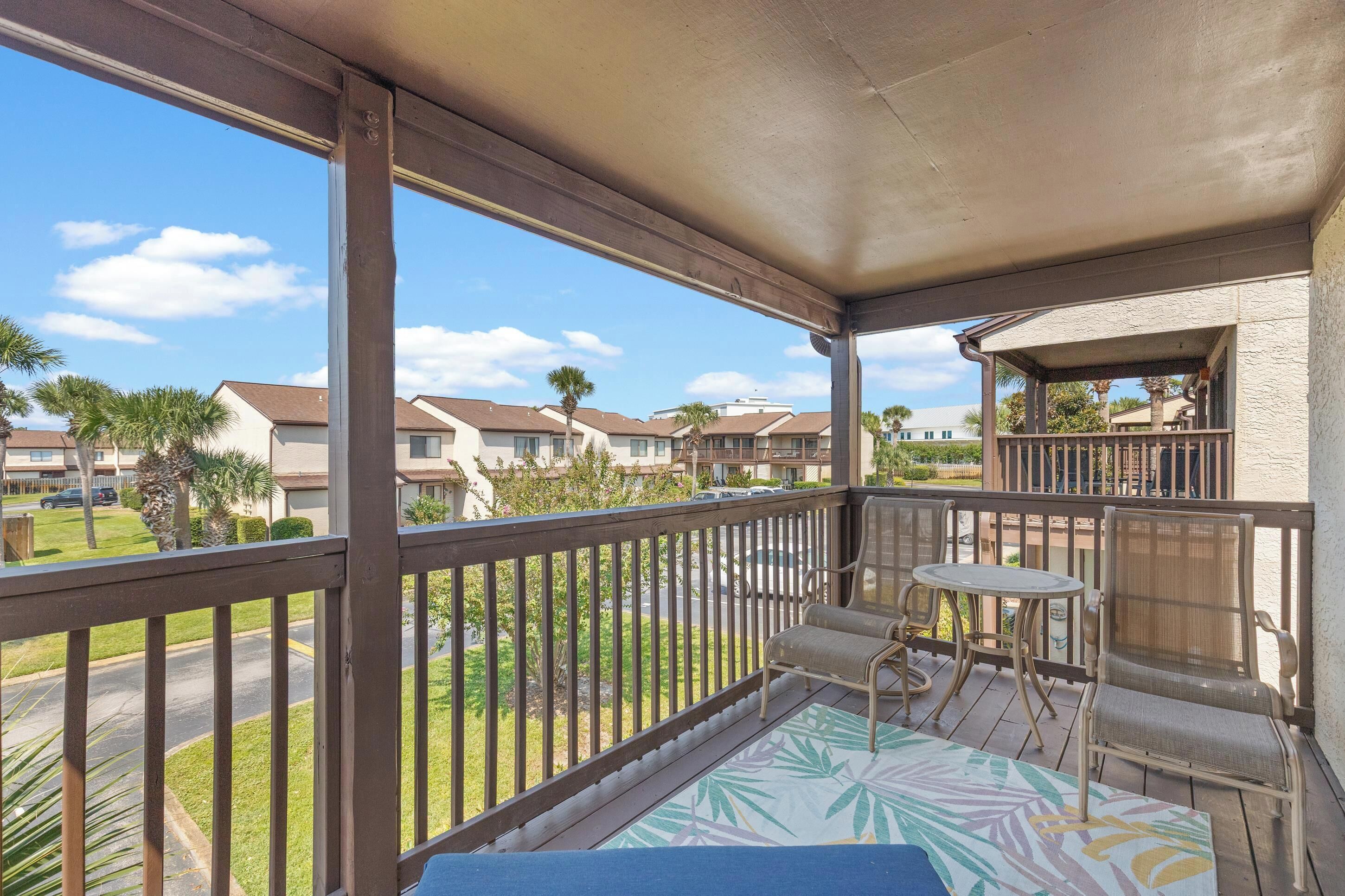 A balcony with a view of neighboring houses, a small table, and a chair.