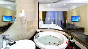 A modern hotel bathroom with a large bathtub, a separate shower area, and a vanity with a mirror.