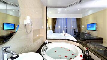 Une salle de bain d’hôtel moderne, dotée d’une grande baignoire, d’une douche séparée et d’un meuble-lavabo avec un miroir.
