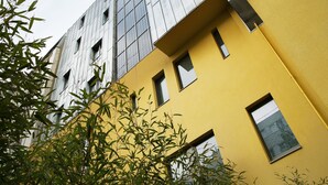 Un immeuble à plusieurs étages, doté d’une façade jaune et de grandes fenêtres.