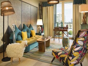 Un salon moderne avec un canapé, un fauteuil à motifs, une table basse et un chien blanc et duveteux.