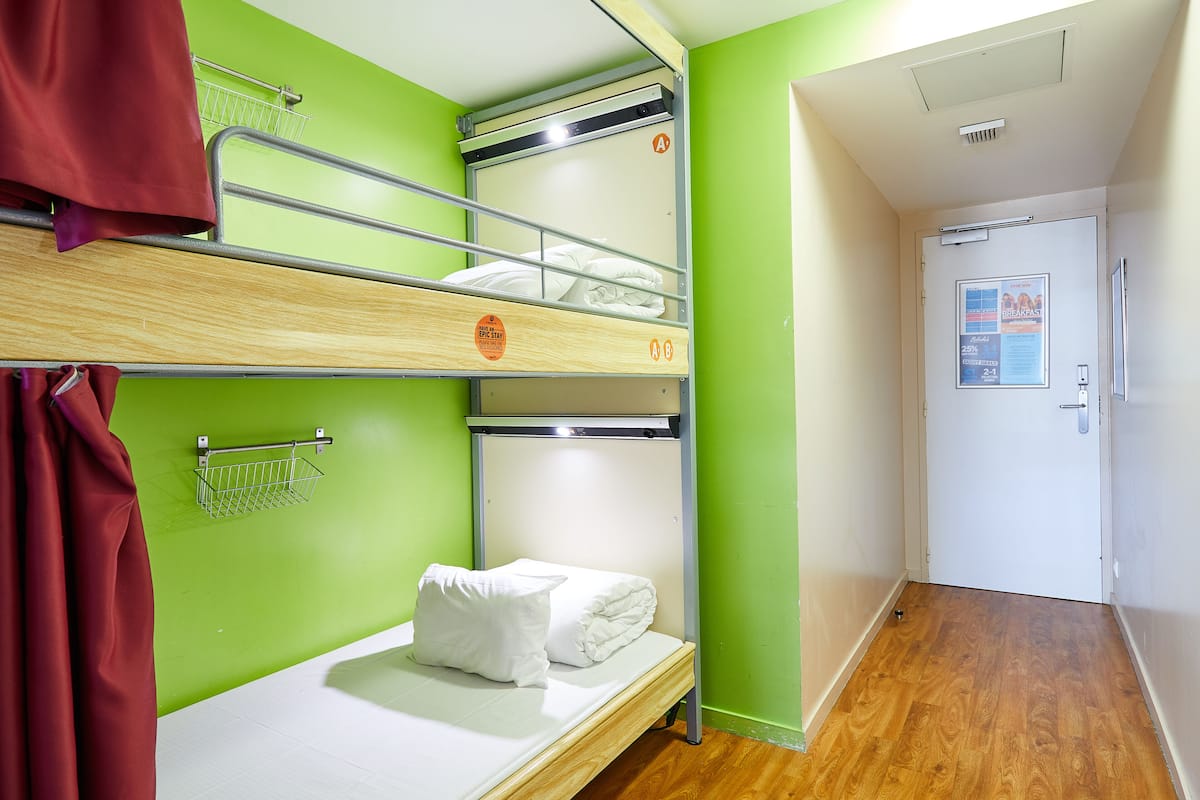A bunk bed room with a green wall, a white door, and a wooden floor.