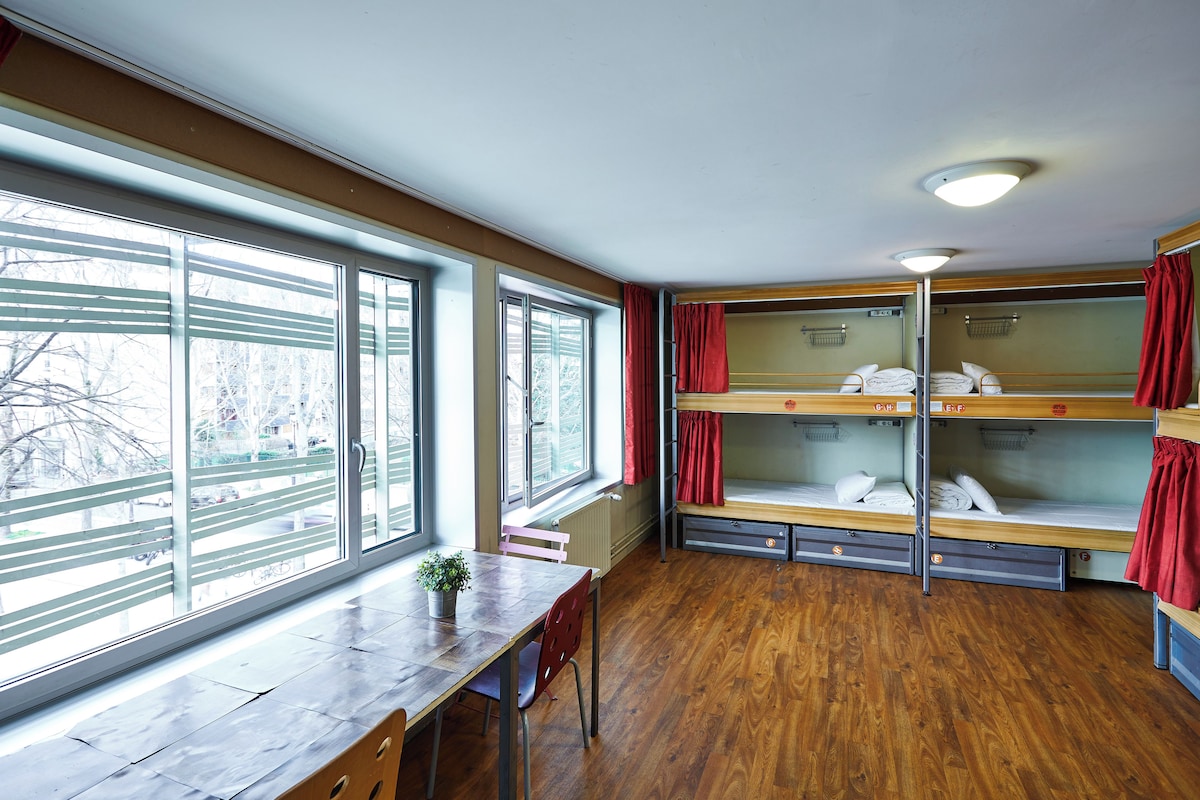 Un dormitorio con literas, una mesa de madera, una silla y una ventana con vistas al exterior.