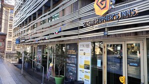 A building with a sign for 'Christopher's Inns' and a 'Backpacker Hostel' sign. There are outdoor seating areas with potted plants and a menu board visible. - St. Christophers Paris Canal (Paris)