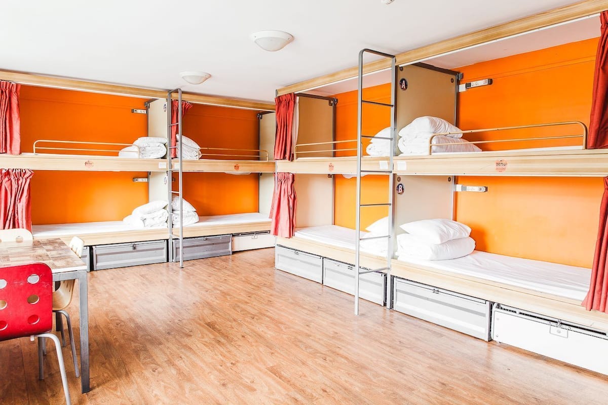 A dormitory room with bunk beds, a desk, and a chair.