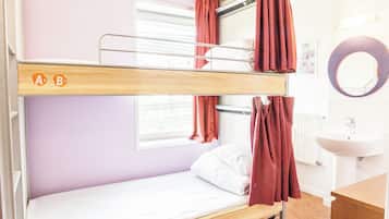 Uma cama beliche com janela, pia e espelho em quarto com paredes lilás.
