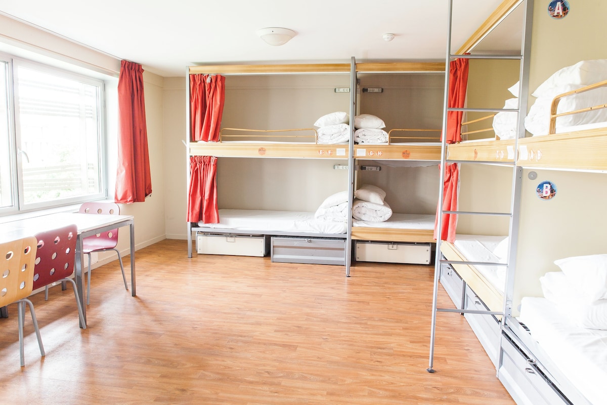 A bunk room with wooden bunk beds, a desk, and chairs.