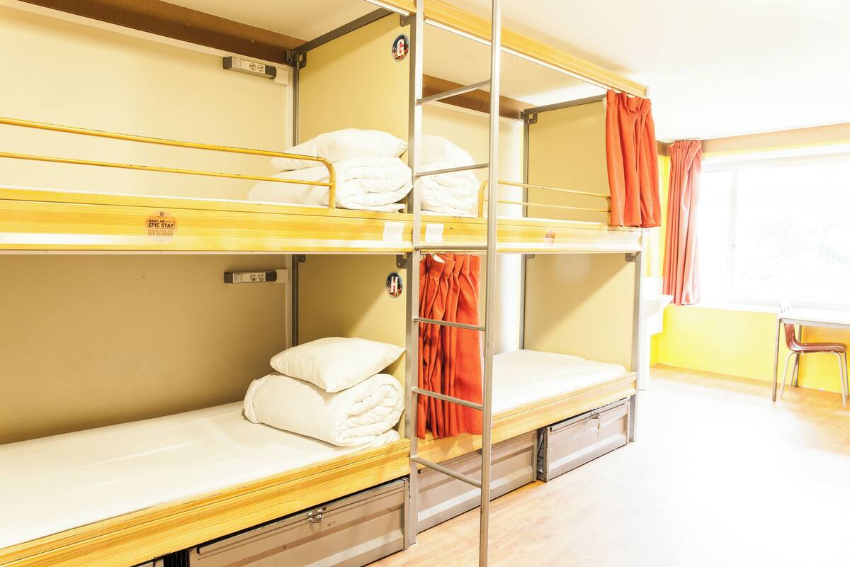 A bunk bed room with a window and a chair.