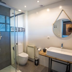 Une salle de bain moderne avec une douche à parois de verre, des toilettes blanches, un radiateur et un meuble-lavabo en bois avec un évier.