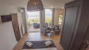 Une chambre à coucher avec un lit, deux fauteuils, une petite table et un balcon avec vue.
