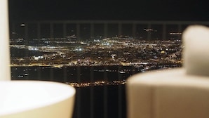 Une vue nocturne d’une ville, prise depuis un point de vue élevé, probablement depuis une chambre d’hôtel.
