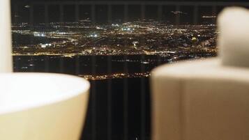 Vista nocturna d'una ciutat des d'un punt elevat, probablement des d'una habitació d'hotel.