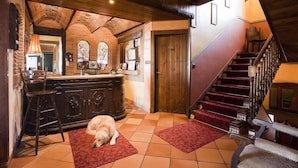 Un intérieur chaleureux avec un escalier en bois, un chien qui se repose sur un tapis et un coin bar agrémenté d’un grand miroir et d’un meuble en bois.