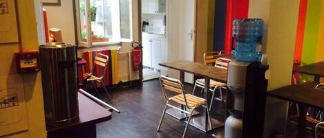 A dining area with a table, chairs, a water dispenser, and a coffee machine.