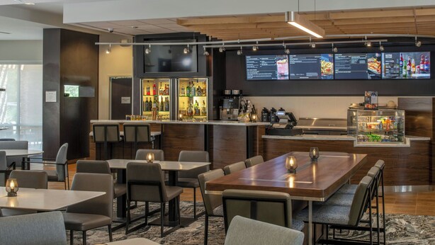 Un restaurant moderne doté d’un bar, de plusieurs espaces de restauration et d’un menu affiché sur écran numérique.