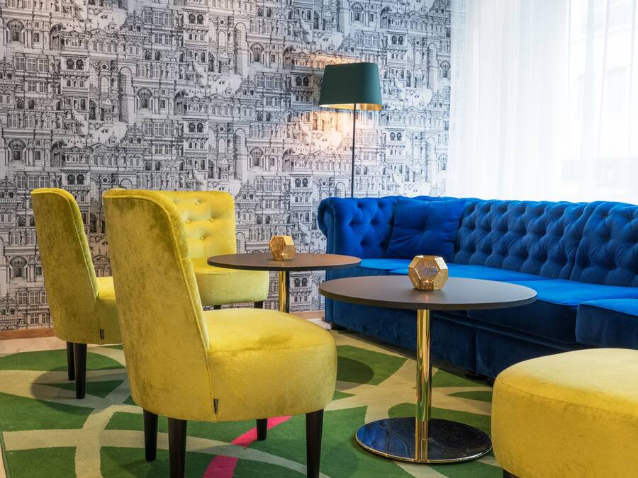 A room with a blue sofa, yellow chairs, and a green lamp.