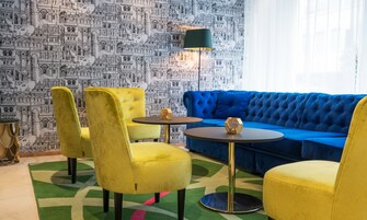 Una habitación con sofá azul, sillas amarillas y lámpara verde.