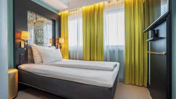 Una habitación de hotel moderna con una cama grande, dos lámparas de noche, una mesita de noche y un ventanal con cortinas amarillas.