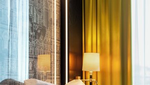 A hotel room with a bed, a nightstand, a lamp, and a window with curtains.