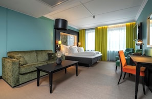 A hotel room with a bed, a sofa, a dining table, and a TV. - Thon Hotel Stavanger (Stavanger)