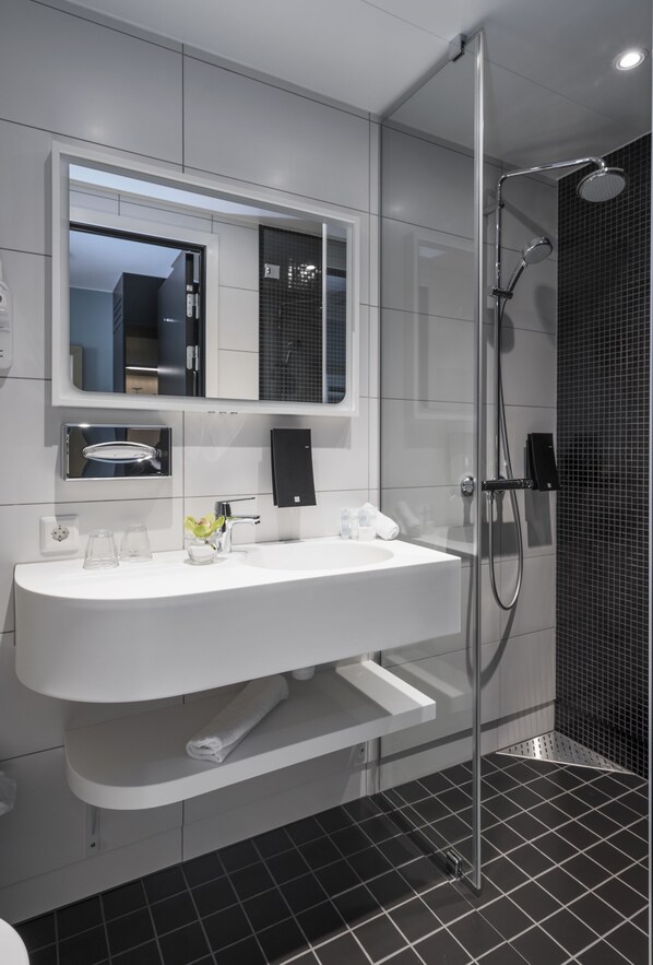 Un baño moderno con un lavamanos grande de color blanco, ducha con cerramiento de vidrio y un espejo sobre el lavamanos.