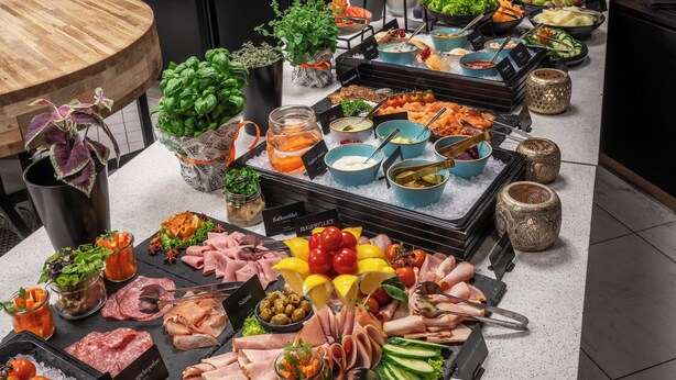 A buffet with various food items and a wooden table.