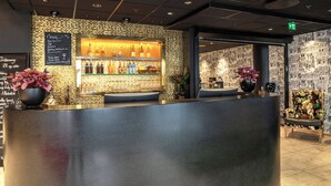 A bar area with a stone wall, shelves with bottles, and a chalkboard menu.