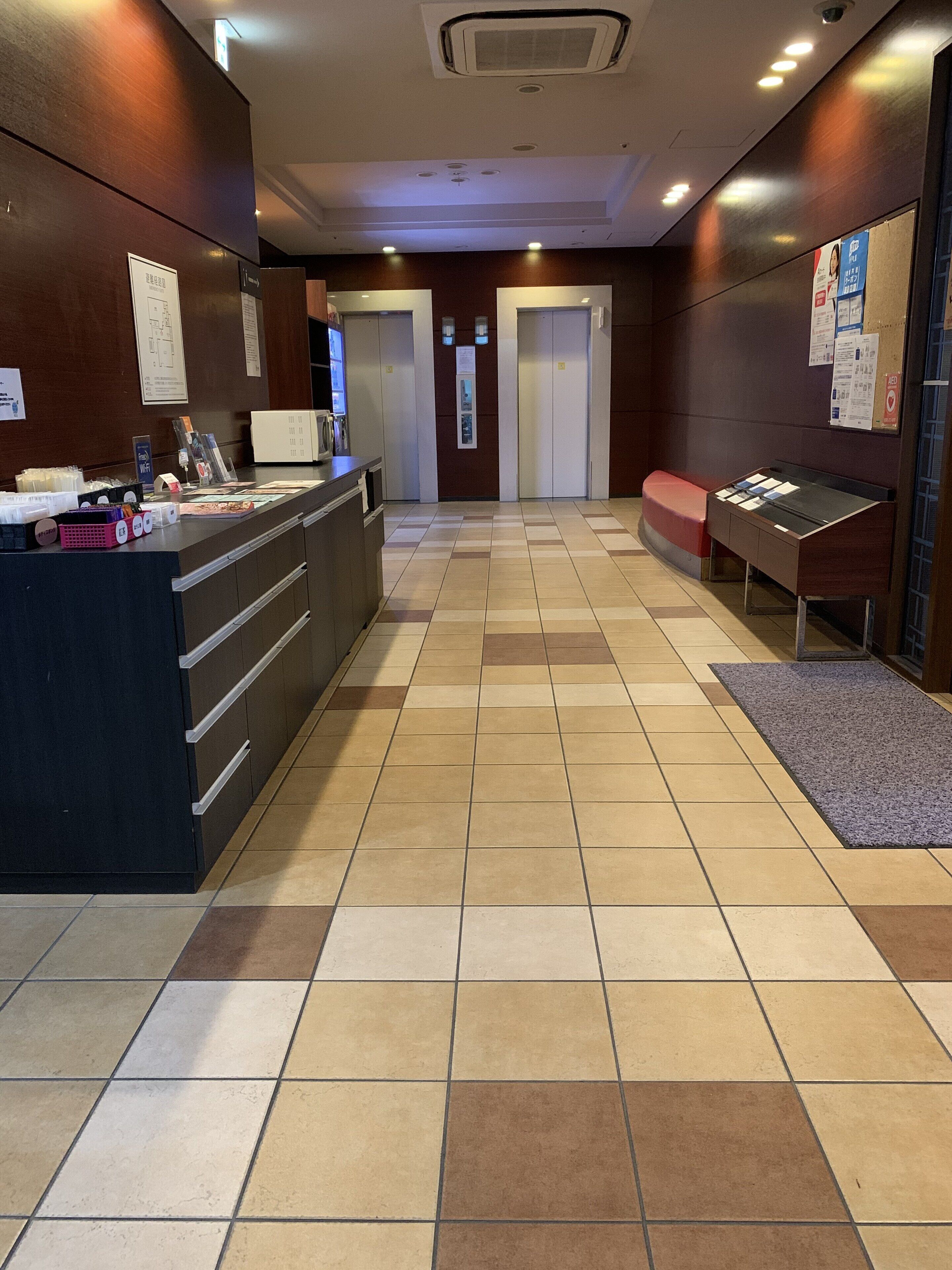 A hotel reception area with a reception desk, a seating area, and a check-in counter.