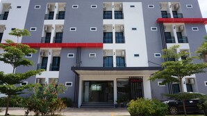 A multi-story building with a modern architectural design, featuring balconies, air conditioning units, and a red awning over the entrance. - NN Place (Udon Thani)