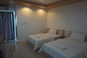 Habitación de hotel con dos camas individuales, un televisor de pantalla plana y baño con cortina de ducha.