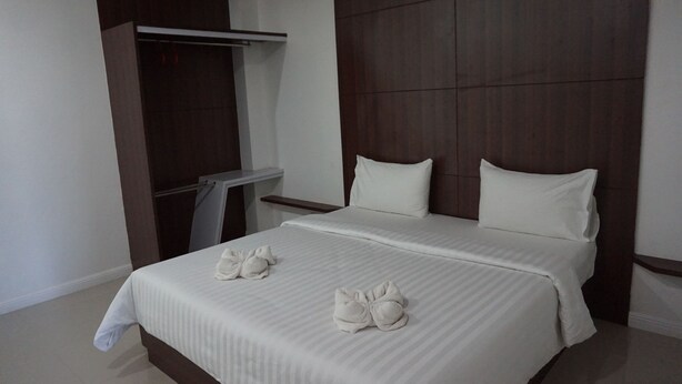 A modern hotel room with a large bed, a wardrobe, and a small table. - NN Place (Udon Thani)