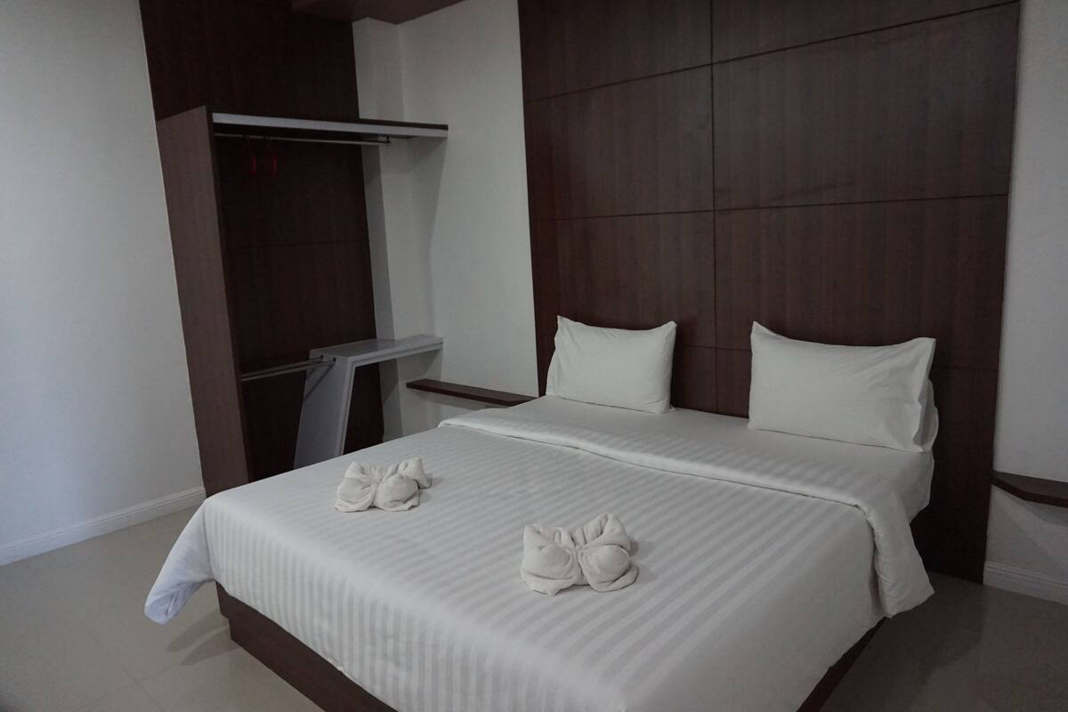 A modern hotel room with a large bed, a wardrobe, and a small table.