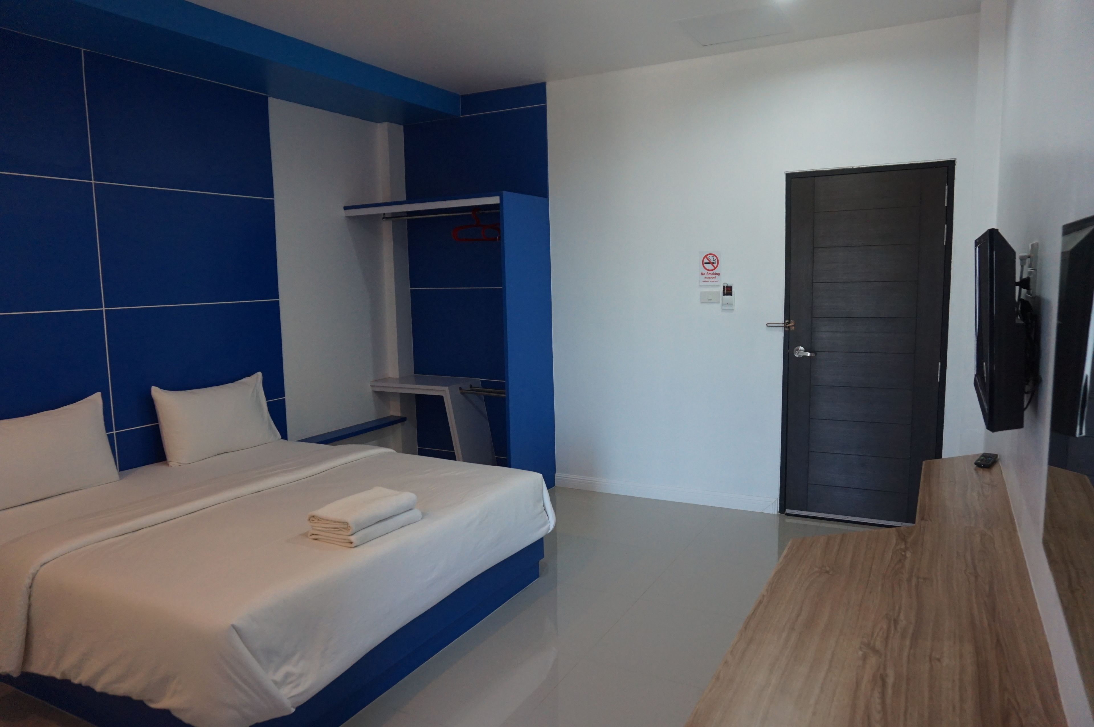 Una habitación de hotel moderna con una cama grande, un armario, un escritorio y una puerta.