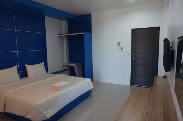 Une chambre d’hôtel moderne avec un grand lit, une armoire, un bureau et une porte.