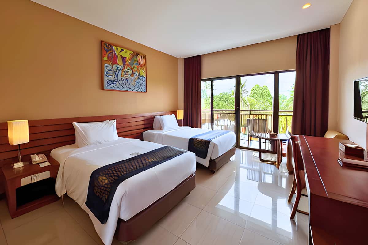 A hotel room with two beds, a desk, a TV, and a balcony with a view of greenery.