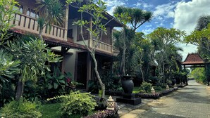 A traditional wooden building with a balcony, surrounded by lush tropical plants and a paved pathway. - Royal Casa Ganesha (Mas)
