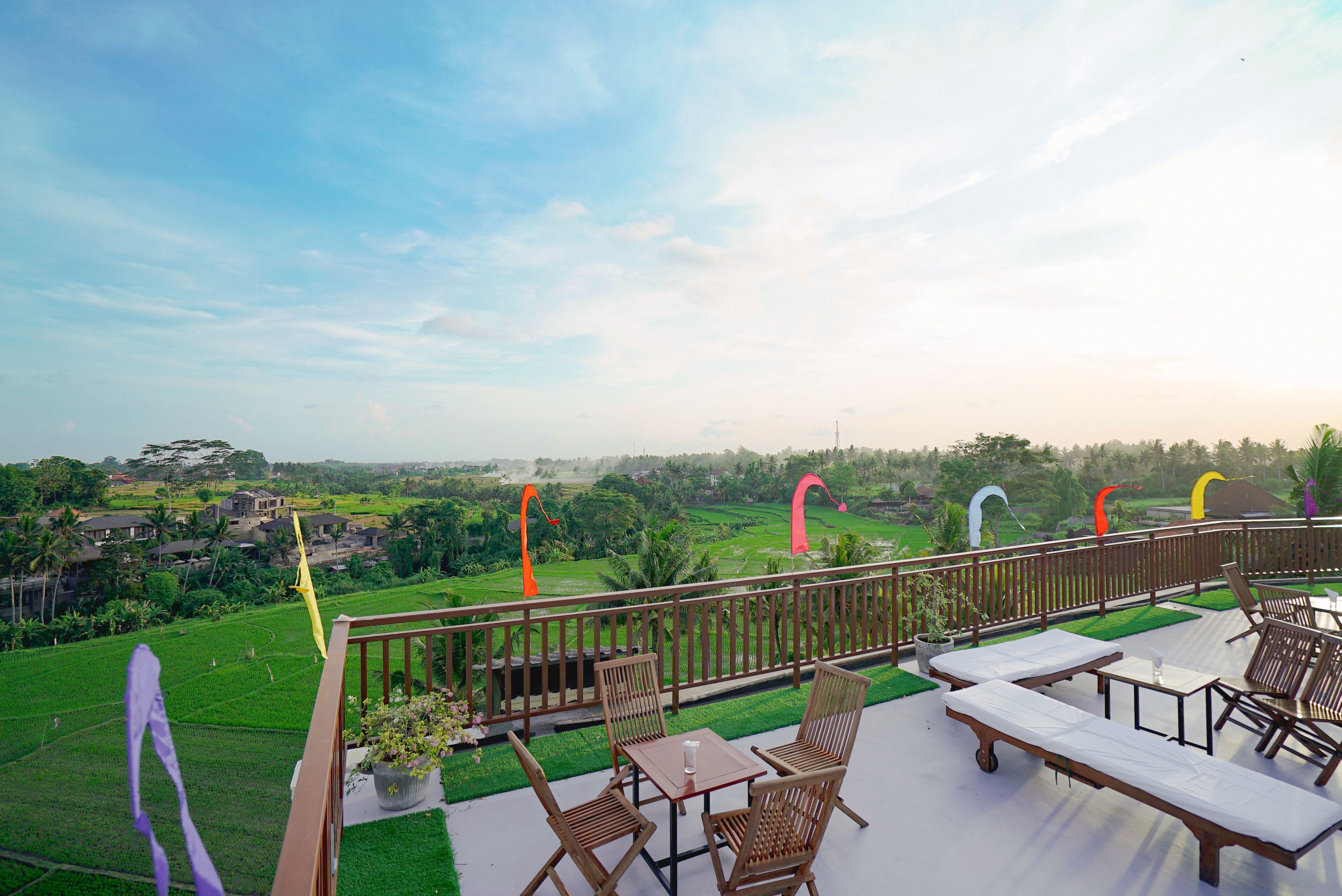 A balcony with a view of a green landscape, wooden furniture, and a railing.