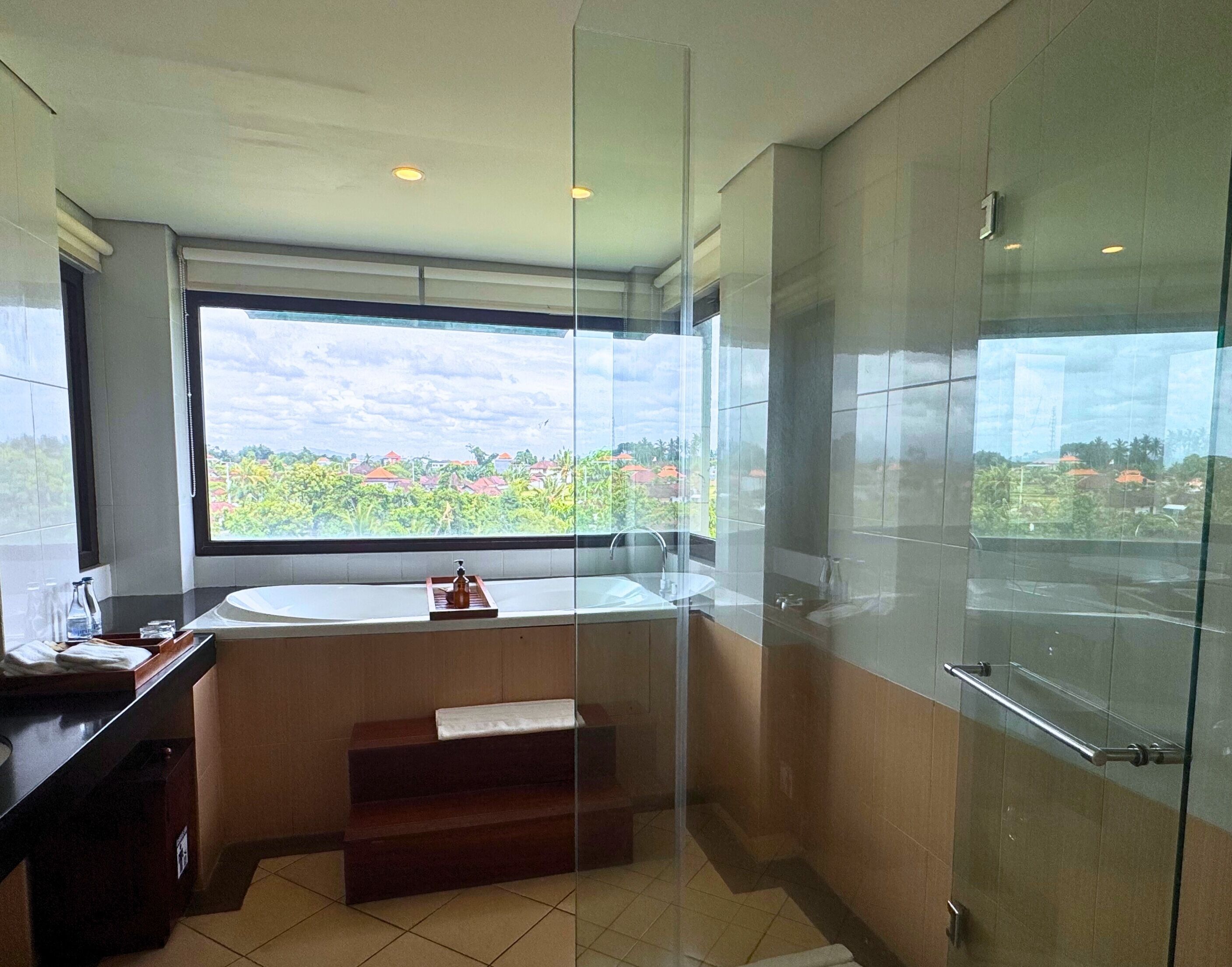 Un baño moderno con un ventanal grande, una bañera y un cerramiento de ducha de vidrio.