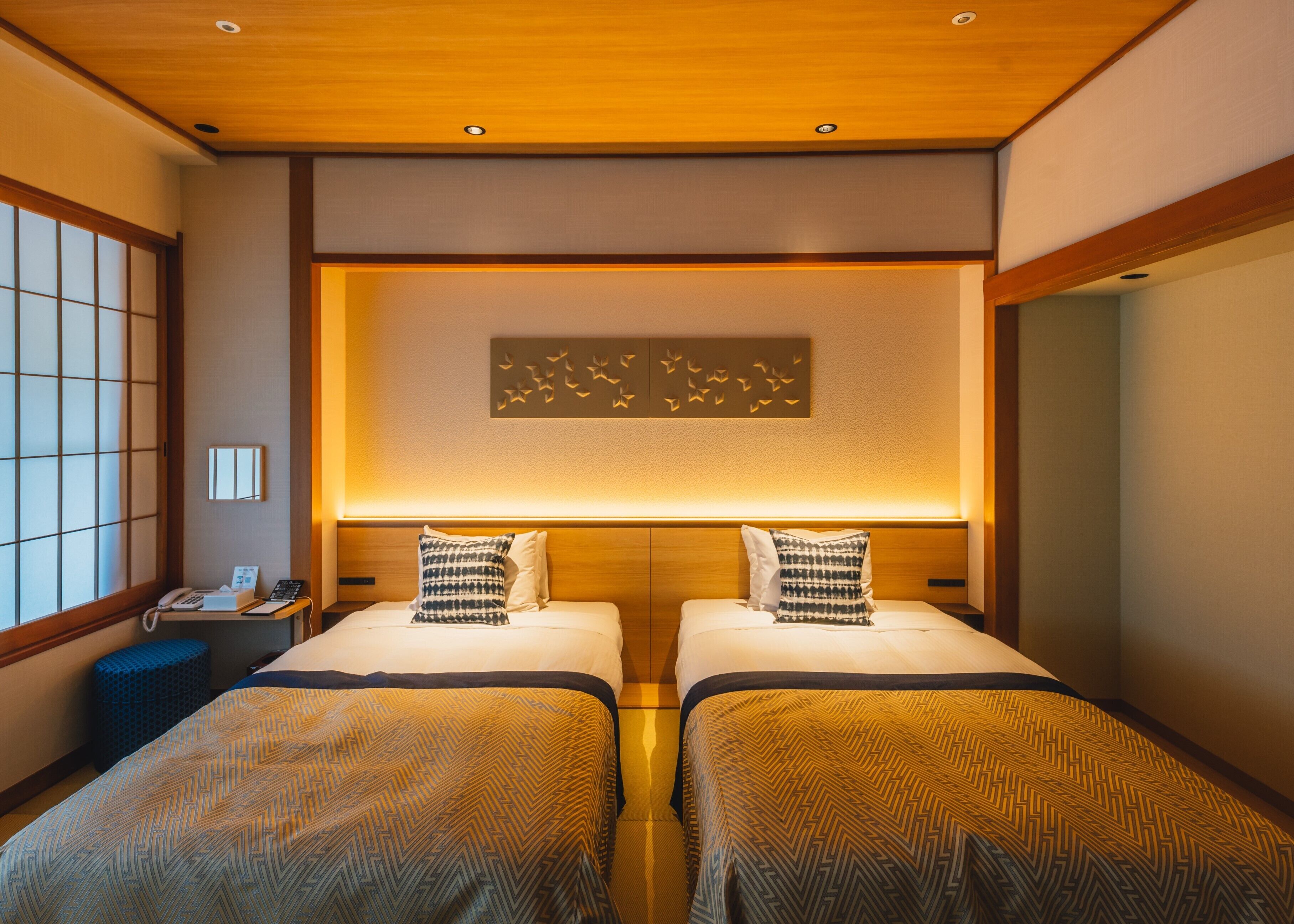 Habitación de hotel con dos camas, techo de madera, teléfono sujeto a la pared y ventana con vistas.