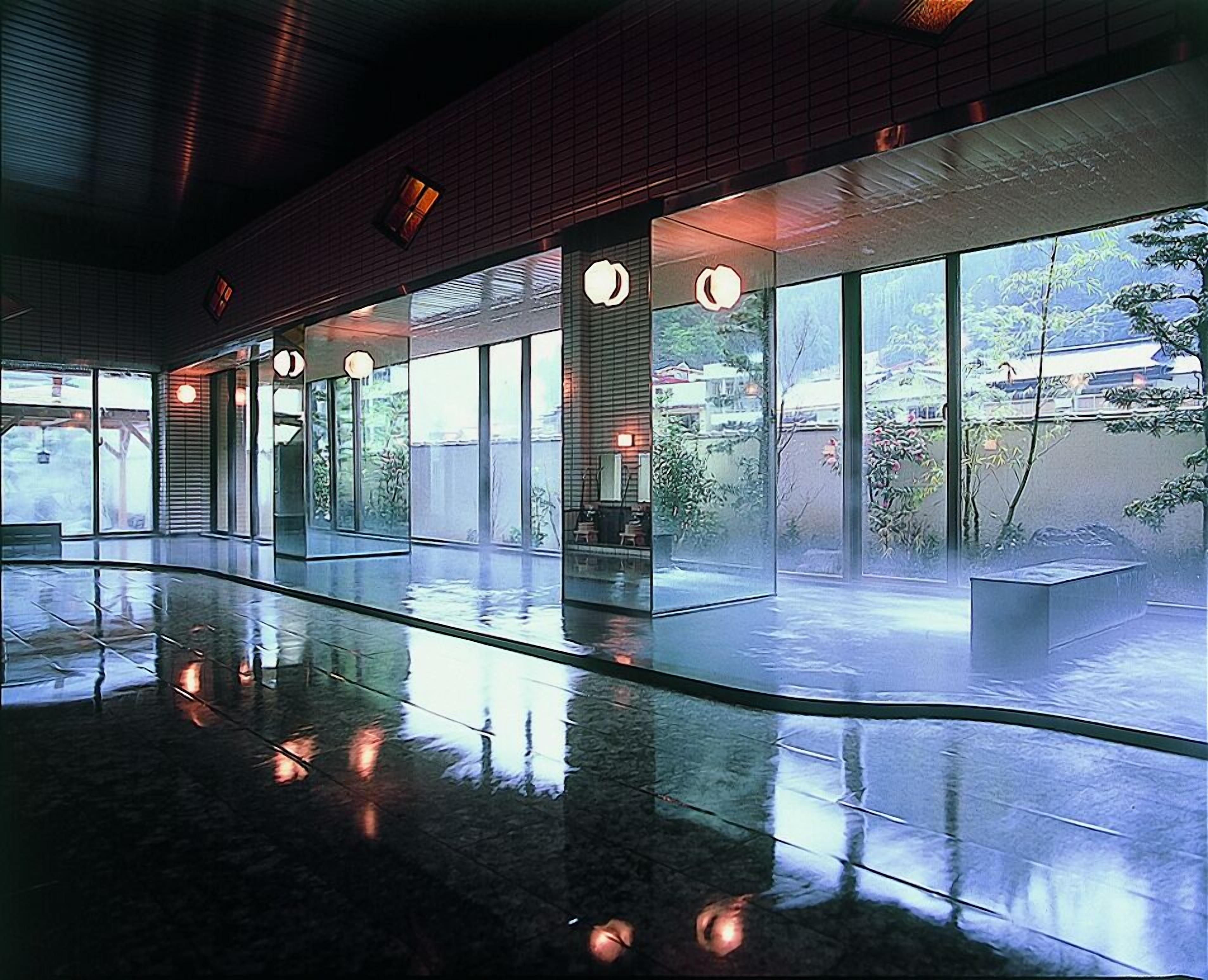 A spacious lobby with a reflective floor, large windows, and round light fixtures.