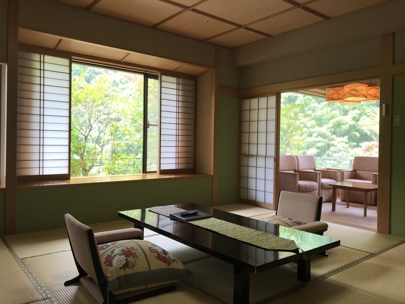 A traditional Japanese room with tatami flooring, a low table, and sliding doors leading to an outdoor seating area.