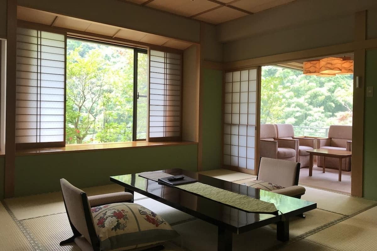 A traditional Japanese room with tatami flooring, a low table, and sliding doors leading to an outdoor seating area.