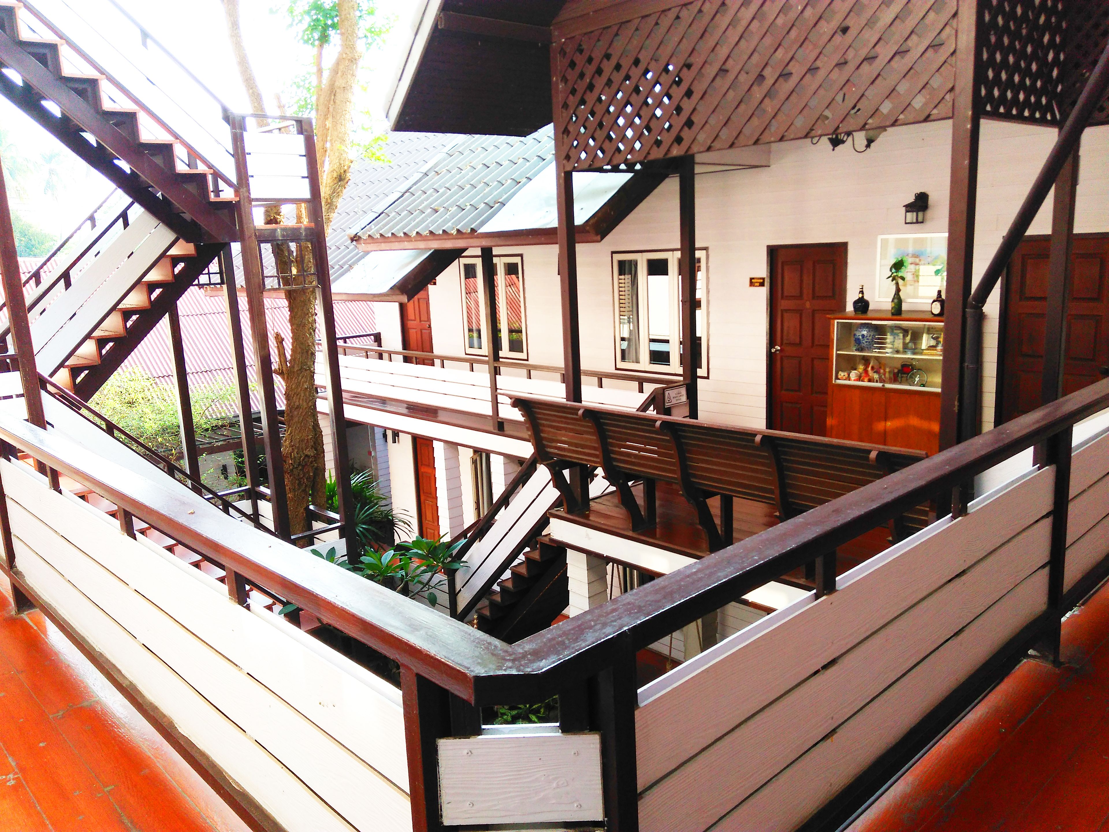 A wooden staircase leading to a balcony with a bench.